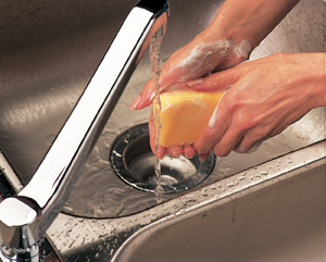 Primer plano de manos en el lavabo debajo de la canilla. Las manos están cubiertas con espuma de jabón.